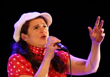 SANDRINE CABADI : « C'EST BEAU COMME CABADI ! » Y'a pas à dire : ce que nous avons dit d'elle il y a peu sur NosEnchanteurs, à l'occasion de la sortie de son nouvel album Qui êtes-vous ?, nous le confirmons, mot pour mot. Avec, plus éclatante encore, la voix de Sandrine Cabadi : un bijou ! (écoutez Je suis jalouse, vous la jalouserez). De part et d'autre, un pianiste-accordéonniste (Christophe Barennes) et un violoniste (Charles Dubrez) : beau duo, tant qu'on regrette un peu que la chanteuse n'en profite pas pour se libérer de son propre clavier qui fait écran entre elle et le public, qui la rend, malgré quelques louables efforts, trop statique. Qu'elle soit de pure création ou de reprises (elle aime partager ce qu'elle aime, La mémoire et la mer inclue), qu'elle lorgne sur la chanson réaliste (son Saint-Lazare de Bruant est d'une très grande justesse d'interprétation) ou qu'elle aille sur un registre proche de la (très bonne) variété, la chanson de Sandrine Cabadi gagnerait à conquérir l'espace scénique, le faire sien, le posséder charnellement. Pour cela, point besoin d'être raccord avec le visuel de la pochette du disque (les petits pois à la Bécaud et surtout la casquette à la Gavroche), le talent de cette chanteuse est tellement évident qu'il doit s'affranchir de tels repères. On nous a tellement gonflé avec des « chanteuses à voix » (je ne cite aucun nom, pas même celui de Ségara, de peur d'en blesser) au répertoire désespérant, que la promesse d'une Sandrine Cabadi est séduisante, entre toute alléchante. Il suffirait de presque rien...