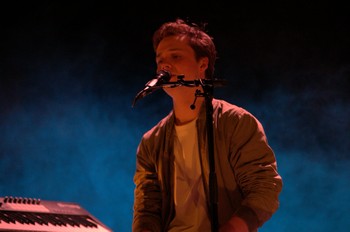     TIM DUP POUR PREMIÈRE PARTIE     Pour la première soirée de ce Printival 2017, Dany Lapointe, la programmatrice, nous présente ce jeune homme, Tim Dup, qui vient de la région parisienne.     Dès les premières notes, Tim Dup nous montre la voie et soigne son son. Nous sommes dans une ambiance électro feutrée qu’il dirige depuis son clavier. Puis sa voix s’élève au dessus des premiers accords, un grain légèrement cassé qui ajoute à cette ambiance veloutée une légère déchirure. Viennent ensuite basse et batterie dirigées par le jeune homme depuis ses machines. L’énergie monte parfois presque jusqu'à la transe avec ses basses si rondes qu’elles font résonner le cœur. Le tout se tient et crée un univers, on s’imagine sur la route en train d’écouter ce spleen tandis que les kilomètres défilent, car ce jeune homme pourrait bien un jour passer sur les ondes s’il rencontre une mélodie qui prend l’air du temps. Et c’est là que Tim Dup pourrait enrichir son travail : des mélodies un peu plus variées, deux musiciens à la basse et à la batterie pour donner une vraie énergie scénique et des textes un tant soit peu plus matures. C’est le petit bémol pour ce chanteur, l’utilisation d’expression comme « fait chier » est parfois un peu gratuite, mais on l’excuse car il est capable de nous sortir aussi des petites perles comme « cette gamme de tons mineurs… moi je les cajole, moi je les prends » dans sa Mélancolie heureuse.     BRUNO HILDESHEIM