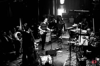 LE CONCERT . Liège, L’An Vert, 1er juin 2019   C’est en trio qu’Ivan Tirtiaux est venu présenter son nouvel album aux Liégeois. S’accompagnant à la guitare – et en piano-solo pour un seul morceau - , il s’est excellemment entouré de Mathieu Verkaeren, maître imperturbable ès contrebasse, à la rythmique solide et rassurante, et de Nyllo Canela, percussionniste aussi fou que brésilien, sosie d’Eric Judor, qui assure le show derrière ses multiples instruments (tambourins, pandeiros, surdos et autres caxixis… On m’a soufflé les noms !). Sept des huit chansons de l’album nous ont été interprétées, mêlées aux titres plus anciens. Dans leur version scénique, elles gagnent en énergie ce qu’elles perdent en contemplation. Le grand Lustucru, par exemple, devient une berceuse effrayante dotée d’effets sonores amusants, tandis que Dans la poitrine, chantée d’une voix déformée sur un rythme tribal, voit sa dimension dramatique accentuée. Les chansons du 1er disque (Charlatan, La course du soleil, Présage…) se dopent quant à elles aux rythmes brésiliens, digne prolongation scénique de la douceur estivale qui régnait sur Liège ce soir-là. La complicité des trois comparses est palpable et le plaisir qu’ils prennent à se produire devant nous a vite gagné l’assemblée, qui ne s’est pas fait prier pour chanter en choeur le refrain de Pourquoi remettre à demain ? Ce fut le point d’orgue d’une belle soirée, où paroles et musiques ont fait jeu égal. On en redemande. (photo Lara Herbinia)
