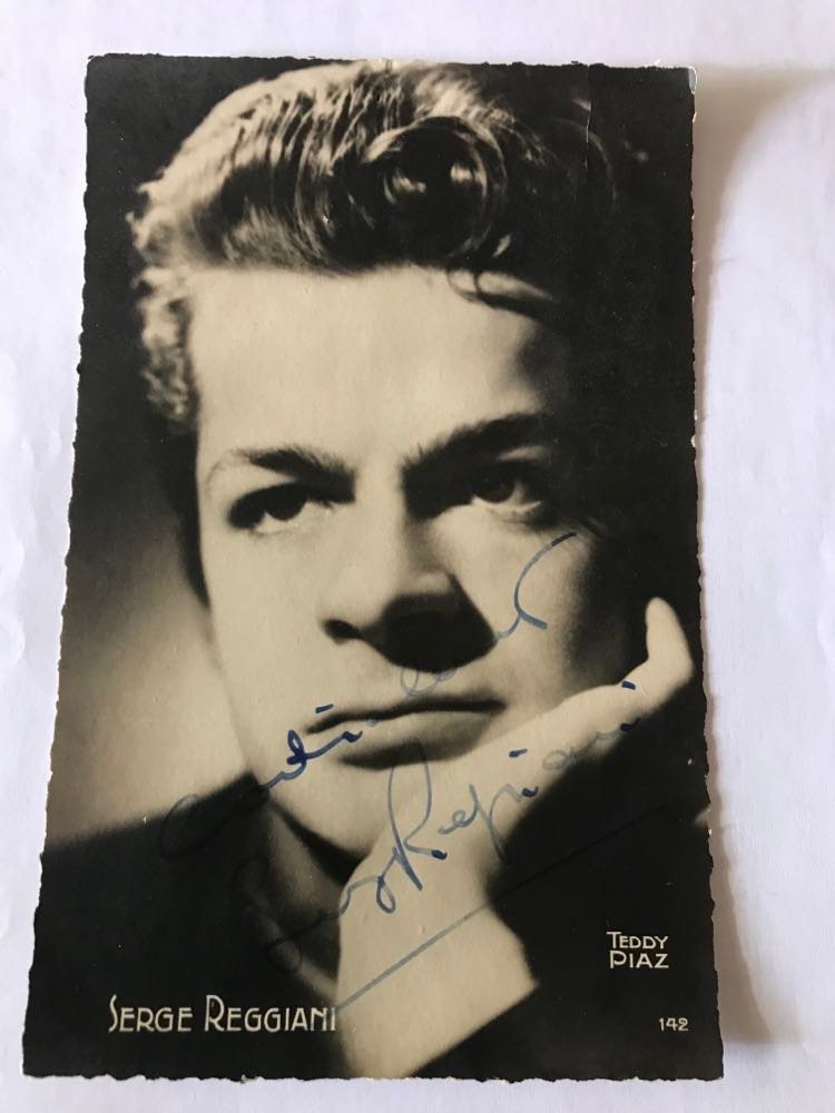 Serge Reggiani, carte postale Teddy Piaz dédicacée, commentée au dos 15 janvier 1943, Le survivant. Je me souviens, j'étais en seconde dans les années 70 dans une Institution pour jeunes filles. Elles ne parlaient que de Reggiani et de ses chansons, semblaient toutes en être amoureuses. Quand j'ai vu ses photos, au lieu du jeune premier romantique ou de la bête de scène à laquelle je m'attendais,  j'ai vu ce visage marqué qui à l'époque me semblait âgé, puis j'ai entendu cette voix tremblante... J'étais étonnée. Mais j'ai vite changé d'avis et compris pourquoi son interprétation fascinait... À l'occasion du centenaire de sa naissance, Polydor sort un nouveau coffret, Reggiani a 100 ans en édition limitée de cinquante chansons en deux CD, peu différent du coffret édité pour les quinze ans de sa disparition, mais comportant  un troisième  CD inédit du concert  à Bobino de 1966, en première partie de Barbara qui le poussera à mettre ses talents de comédien et d'interprète au service de la chanson,  et un DVD d'1H30 d'archives TV INA, dont les deux émissions complètes Discorama de 1968 et 1971. Outre les chansons les plus célèbres de l'artiste, écrites par Dabadie, Lemesle, Dimey, Tisserand, Anne Sylvestre...les poètes Hugo,Rimbaud, Baudelaire, Prévert... on y redécouvrira La vie c'est comme une dent, de Boris Vian, chantée en 1967, Dans le miroir, de Dréjac (enregistrement 1972), Ce soir mon amour, de Moustaki, de 1973, L'exilé, 1981 de Claude Lemesle /Alice Dona...   Il est à noter que Polydor sortait déjà en 2006 un coffret de cinq CD pour 100 chansons. Catherine LAUGIER